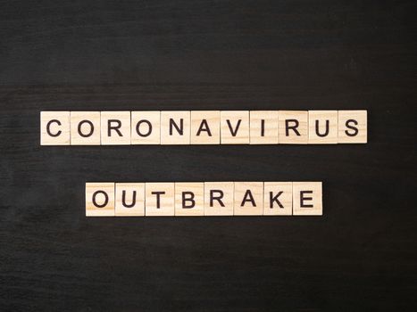 Coronavirus outbreak words made of wood block. Coronavirus outbreak text on dramatic atmosphere black wooden table. Coronavirus concept top view.