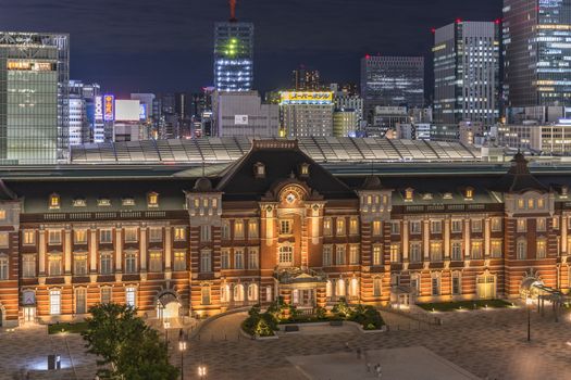 Night view of Marunouchi side of Tokyo railway station in the Chiyoda City, Tokyo, Japan.  The station is divided into Marunouchi and Yaesu sides in its directional signage. The station first called Central Station was built in 1914 directly in front of the Imperial Palace gardens. The three-story station building was designed by architect Tatsuno Kingo who also designed Manseibashi Station and the nearby Bank of Japan building. Much of the station was destroyed in B-29 firebombing on May 25, 1945. The bombing shattered the impressive rooftop domes. The station was quickly rebuilt within the year, but simple angular roofs were built in place of the domes, and the restored building was only two stories tall instead of three. 