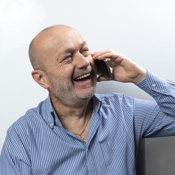 A middle-aged man laughs during a cell phone conversation