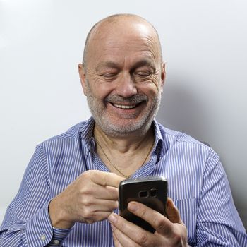 A middle-aged man laughs during a cell phone conversation