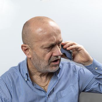 A middle-aged man argues during a cell phone conversation