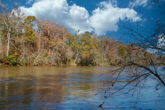 A wide, calm river in late autumn under clear blue skies