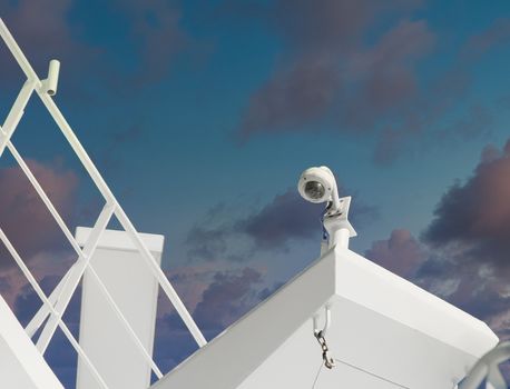 A security camera against blue sky on white superstructure of a cruise ship