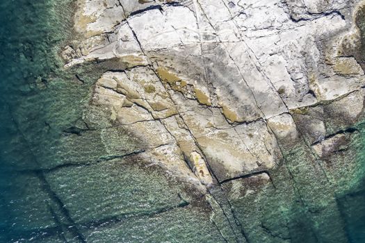 an aerial view of the beach with flat rocky cliffs immersed in the sea, Duga Uvala, Istria, Croatia