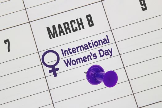 A close up to a Calendar on March 8 with the text: International Women's Day with a purple pin