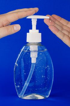 A close up of a person applying hand sanitizer on a dark blue background