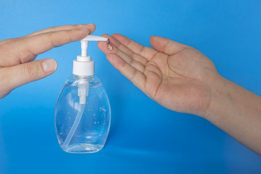 A person putting hand sanitizer isolated on a blue background