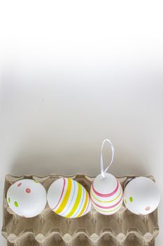 Colorful easter eggs on a cardboard holder with a white background and soft shadows