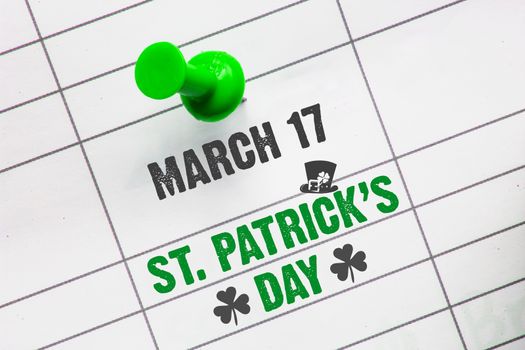 A close up of a calendar on March 17 with a pin the text: St. Patrick's Day, a clover and an irish hat