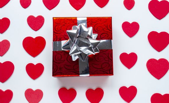 A red present with red hearts around on a white background