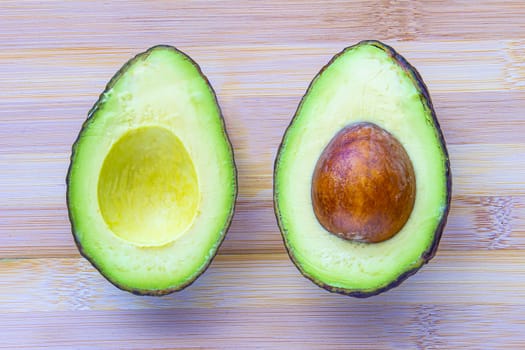 An avocado cut in half on a wooden cutting board