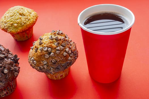 Single-use coffee Cup and muffin on red background