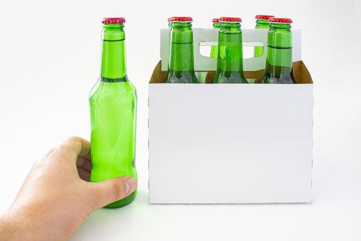 A person holding a beer with a six pack of a green beer bottles isolated on white background