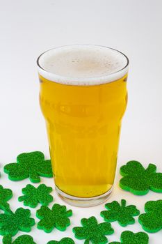 A Pint of beer with green clovers around