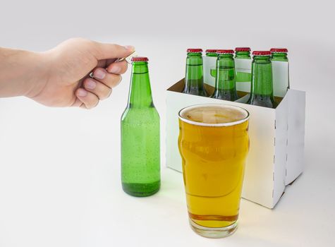 A person opening a Pilsner Style Lager green bottle sic pack with a full pint of beer