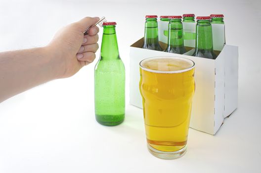 A person opening a Pilsner Style Lager green bottle sic pack with a full pint of beer