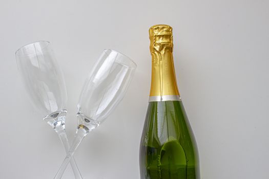 Unopened champagne bottle with cups on a white background