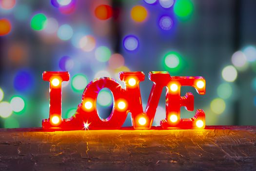 LOVE sign Bedroom Decor with Lights LED Marquee Letters on red with colourful defocused lights background.