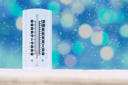 Indoor and Outdoor Thermometer that Shows a very low temperature on Fahrenheit and Celsius with defocus background and falling snow on the background.