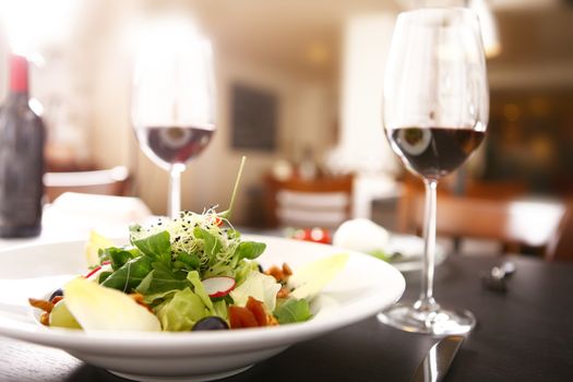 salad and red wine and tomato with mozzarella in a white plate