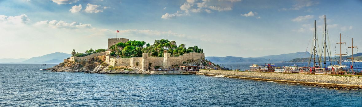 Kusadasi, Turkey – 07.18.2019.  Kusadasi castle in Turkey and pleasure boat parking on a summer evening