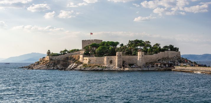 Kusadasi, Turkey – 07.18.2019.  Kusadasi castle in Turkey and pleasure boat parking on a summer evening