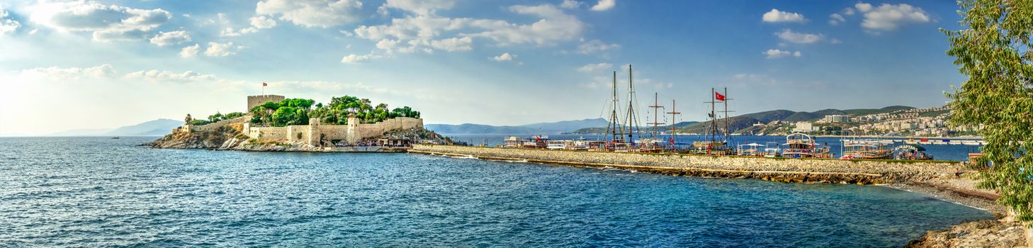 Kusadasi, Turkey – 07.18.2019.  Kusadasi castle in Turkey and pleasure boat parking on a summer evening