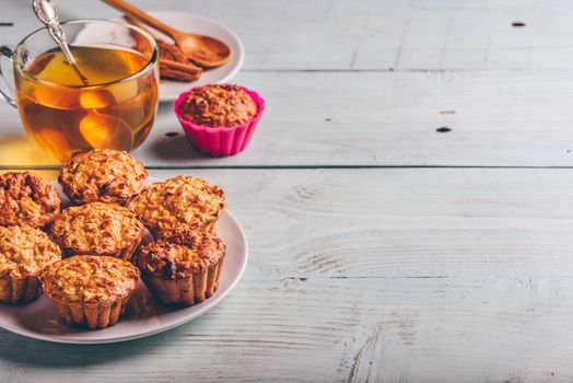 Healthy Dessert. Oatmeal muffins with cup of green tea over light wooden background. Copy Space.