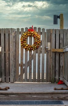 A gold wreath at Christmas hanging on a gate in walkway toward beach