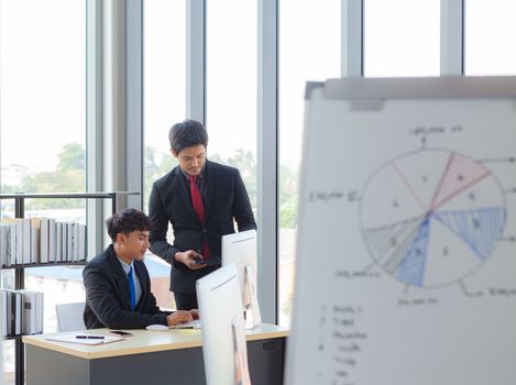 The young manager is introducing employees to increase work efficiency through a computer monitor in a modern office.