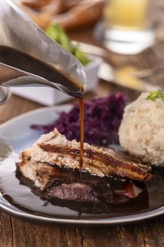 pouring sauce over roasted pork with dumpling