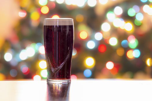 A Stouts Dark Beer with Christmas lights on the background. Guinness dark Irish dry stout. Horizontal View