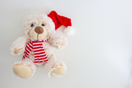 Horizontal view of a light brown teddy bear with a santa hat