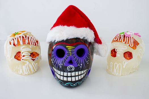 A Black Traditional Mexican sugar skulls with Santa hats. Mexican Christmas.(calaveritas de azucar para navidad en México) mix cultures.