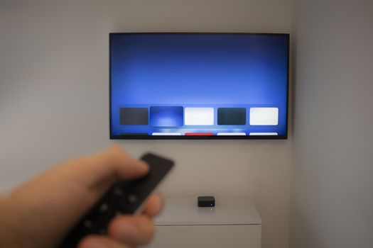 Person holds TV remote using a generic application on a smart TV.