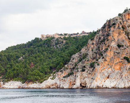 The fortified walls of Alanya Castle in Southern Turkey as viewed from the Mediterranean Sea.  The castle is located on a rocky peninsula and dates back to the 13th century.