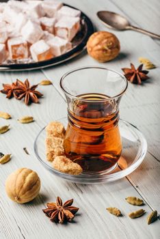 Tea in armudu with turkish delight Rahat Lokum and different spices over wooden surface