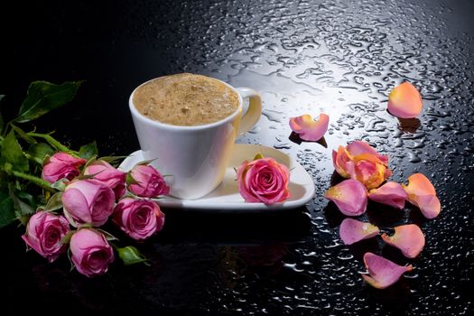 Three red roses on a black background with water drops