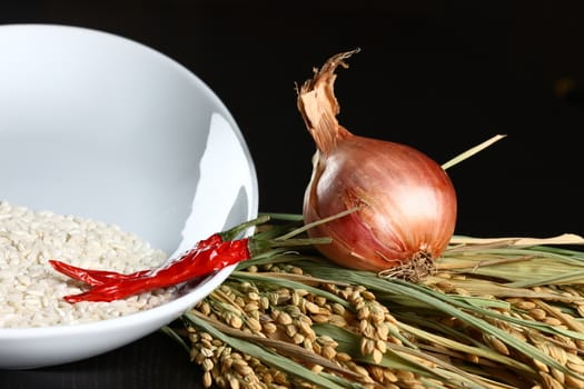 Onions, rice and chilli. Healthy organic raw food ready for cooking on dark background