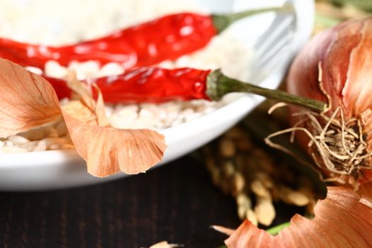 Healthy organic raw food ready for cooking. Close up of onion peel with rice corn laying on a table with a white plate