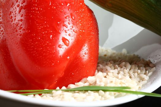 Healthy fresh organic food with water drops with rice and pepperoni in a white plate with a green leaf