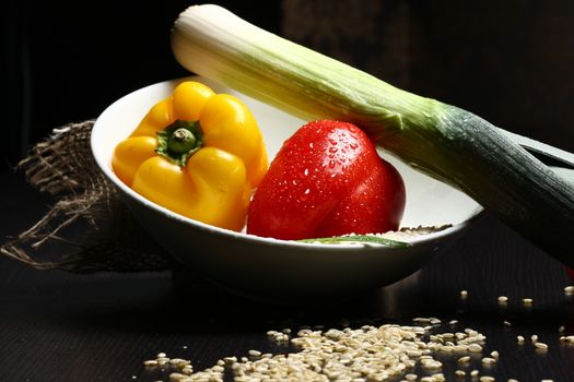 Close up of healthy fresh organic food with water drops with rice and red and yellow pepperoni and green leek and rice corn