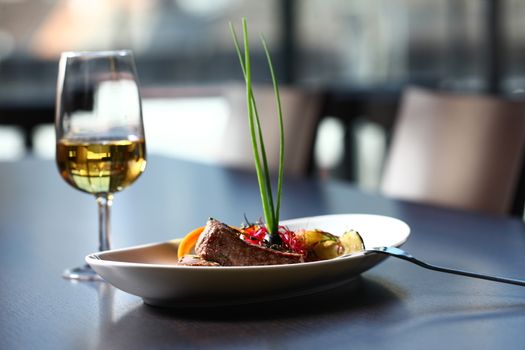 a good meal with wine. close up of a dish with meal, rice and mushrooms and a glass of wine in background . On clean grey table with chair showing in the background