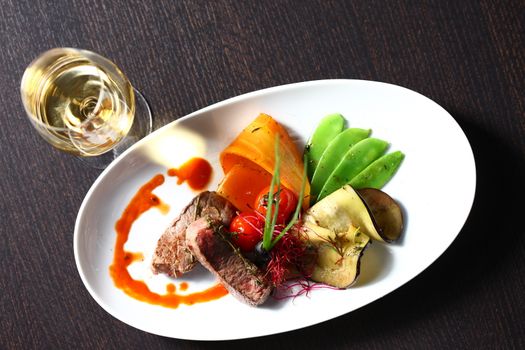 a good meal with wine. Shot from above with copy space and oval plates and a glass of wine on wooden table