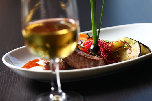 a good meal with wine. Close up of out of focus wine glass with dish in the background