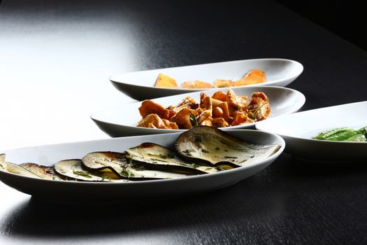 food white plates on table top, ready to served for guests in a dark setting. Mushrooms and leek cooked