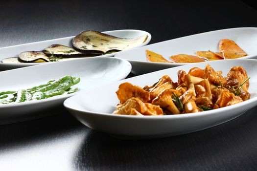 food plates on table top, ready to served for guests in a dark setting, Mushrooms and leek cooked and other side dishes