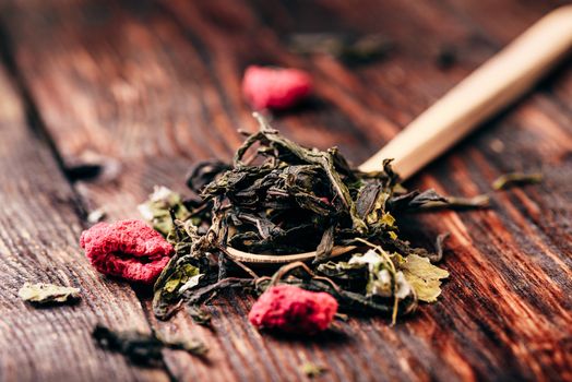 Wooden spoon of raspberry herbal tea over wooden table