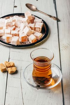 Tea in arabic glass with turkish delight Rahat Lokum over wooden surface