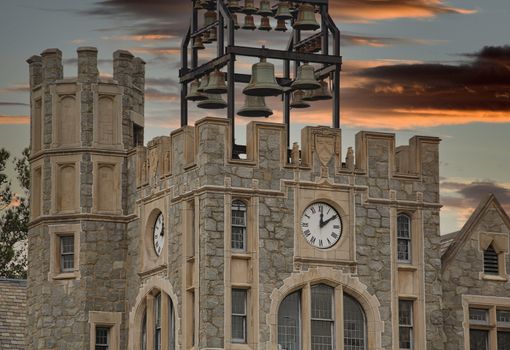 An old stone building with a clock tower and old brass bells